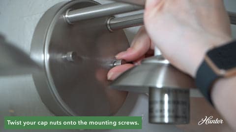Twisting the cap nuts onto the mounting screws.