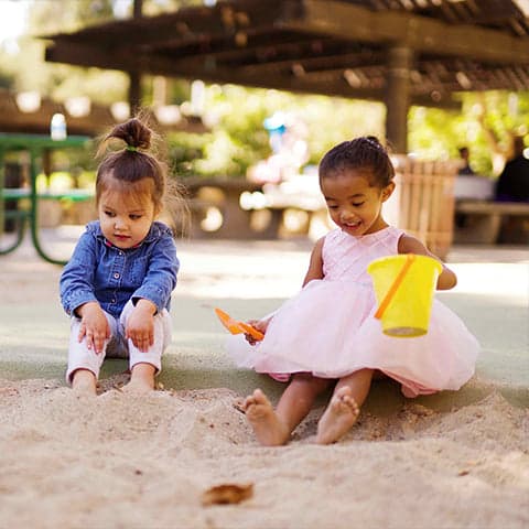 Two children playing outside in the sand