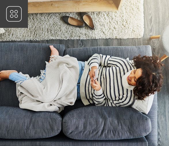 woman controling her fan with the convenient HunterSMART app from the comfort of her sofa