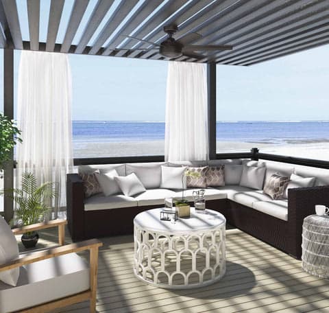 Jetty outdoor fan in Matte Silver hanging under a pergola on the beach.