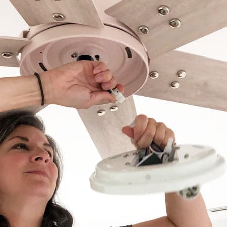 Image of a woman removing the lighting fixture from their fan.