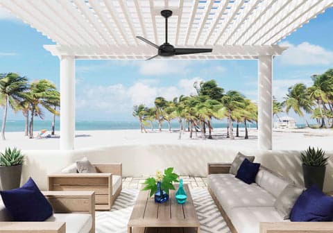 Trimaran outdoor fan in Matte Black hanging under a pergola on the beach.