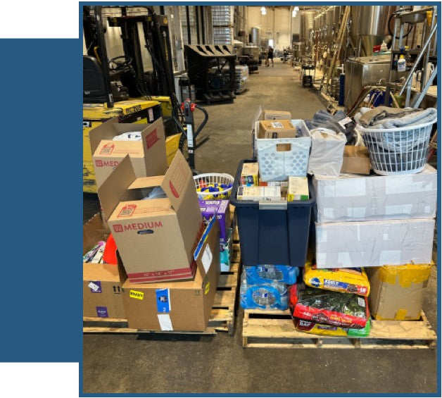 Two pallets loaded with boxes, storage bins, laundry baskets, and packages inside a warehouse.