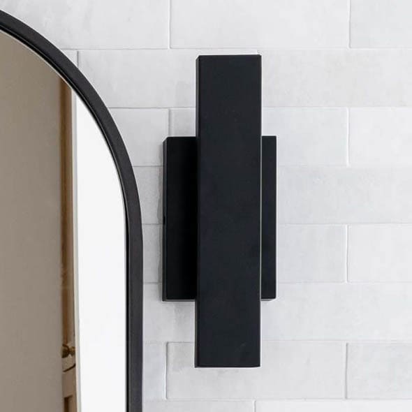 Canoga wall sconce in matte black on white tile.